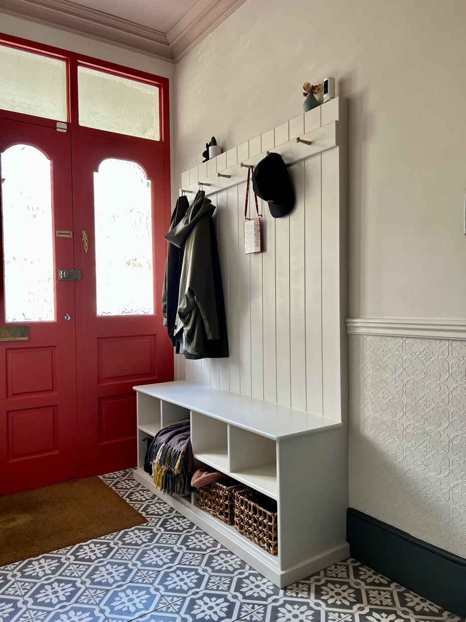 Hallway with red front door, custom coat storage, and encaustic patterned floor tiles