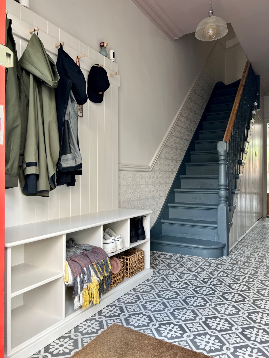 Staircase with deep blue-grey paint and restored Victorian balustrade above patterned tiles