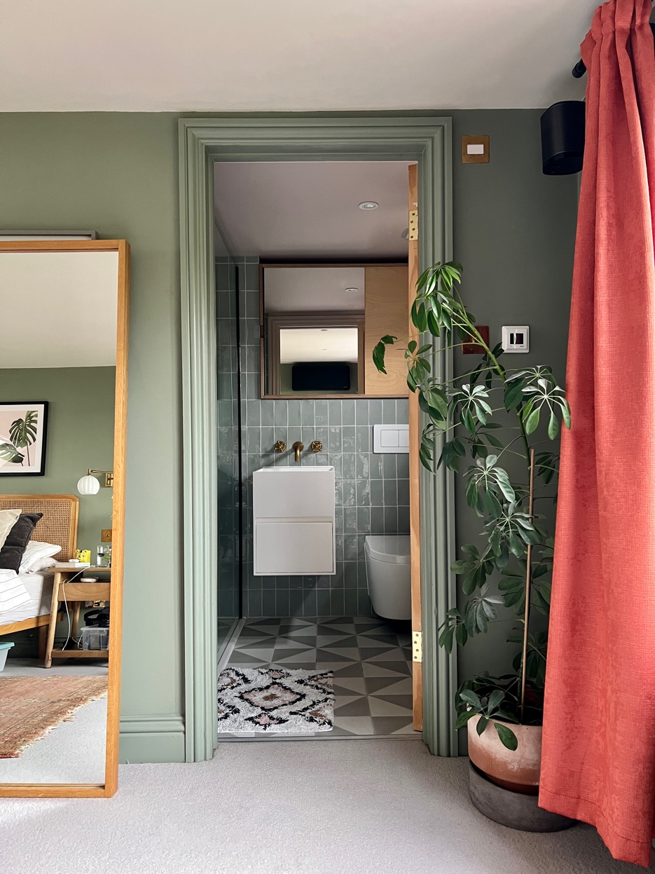 Loft en-suite viewed through doorway from bedroom with blue-green zellige tiles and geometric floor tiles