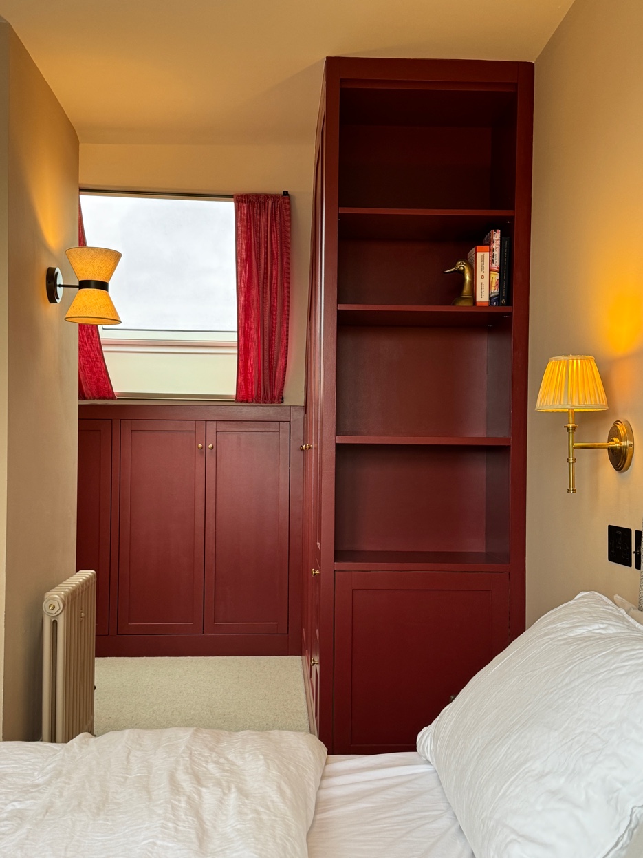 Burgundy bookcase joinery built into the angled ceiling of the loft bedroom