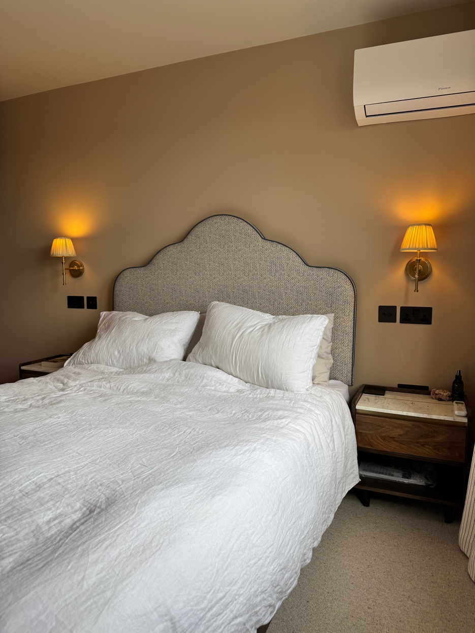 Calm bedroom with curved headboard and brass wall lights — Wimbledon