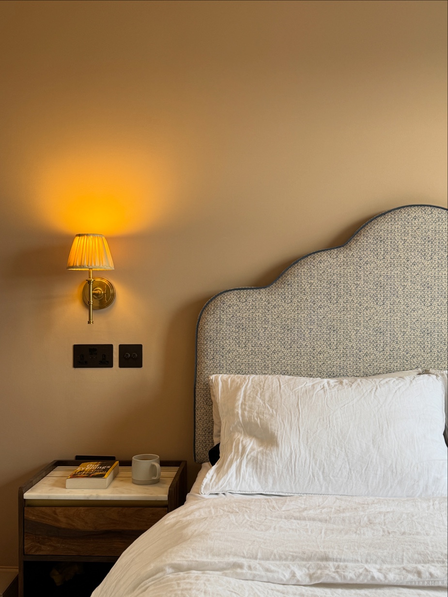 Bedroom bedside detail with brass wall light and walnut bedside table