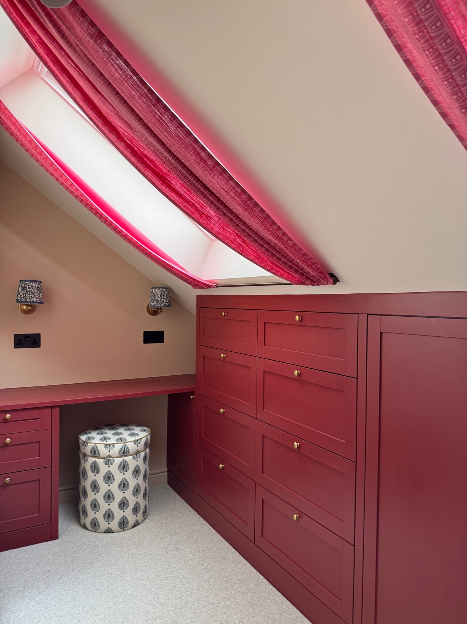 Dressing room with floor-to-ceiling burgundy joinery, drawers, vanity desk, and skylight with raspberry curtains