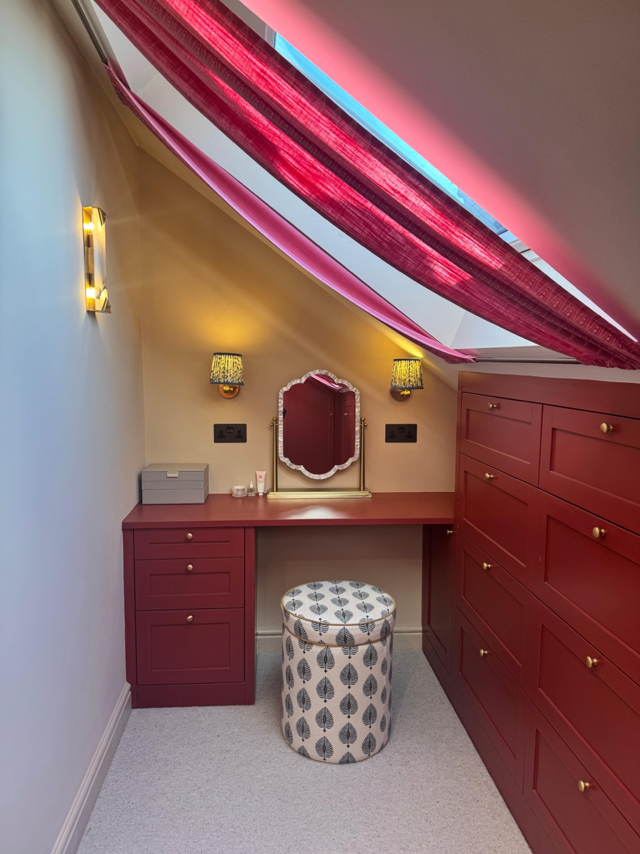 Dressing room vanity with table-top mirror, skylight with raspberry curtains, burgundy joinery, and patterned stool