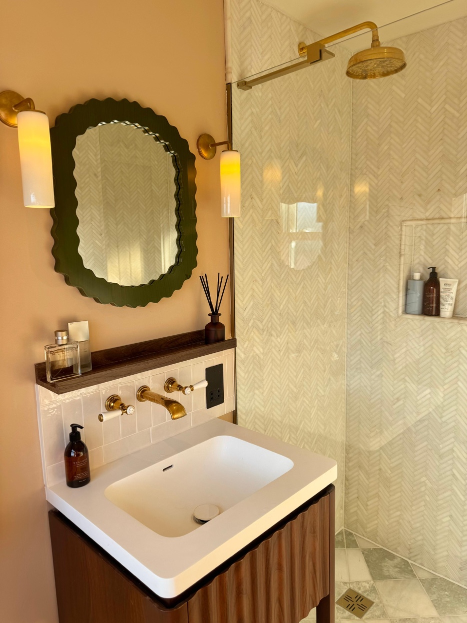 Close-up of marble vanity with brass taps and pendant light
